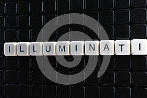 Illuminati text word crossword. Alphabet letter blocks game texture background. White alphabetical letters on black