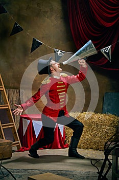 Illusionist or showman. Cinematic portrait of emotive man retro circus entertainer announces start of show isolated over