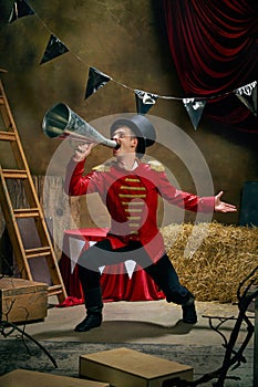 Illusionist or showman. Cinematic portrait of emotive man retro circus entertainer announces start of show isolated over