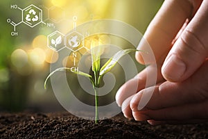 Illustration of chemical formulas and woman protecting young green seedling in soil, closeup