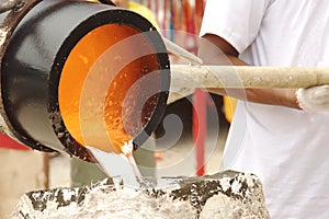 Illustration of molten metal being poured from a foundry crucible statue