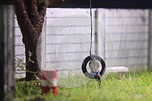 Illustration Photo, Gadget Freak or addicted, Sitting Man Holding Smartphone at swinging from used car tire in the yard