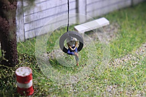 Illustration Photo, Gadget Freak or addicted, Sitting Man Holding Smartphone at swinging from used car tire in the yard