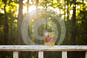 Illustrative editorial image of a shot of whiskey on a porch rail.