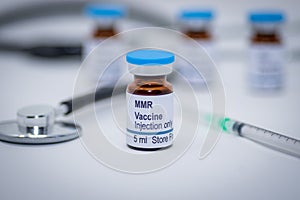 Illustrative picture of measles mumps and rubella MMR vaccine vial with syringe and stethoscope