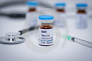 Illustrative picture of measles mumps and rubella MMR vaccine vial with syringe and stethoscope photo