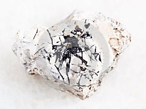 Ilmenite black crystals on raw stone on white photo