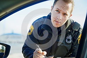 Im afraid Im gonna have to write you up. a handsome young male traffic officer issuing a ticket at a roadblock.