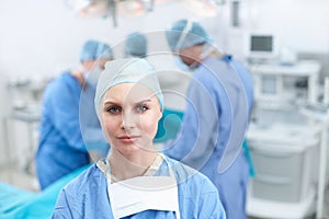 Im dedicated to being my best. Portrait of a female surgeon with her colleagues operating in the background - Copyspace.