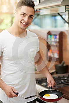 Im so egg-cited to dig in. a young man preparing breakfast at home.