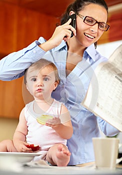 Im feeling a bit left out. Shot of a frustrated-looking single mom feeding her baby while trying to talk on the phone