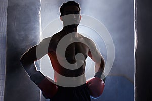 Im fight ready. Cropped portrait of a silhouetted young male boxer standing with his hands on his hips after a workout