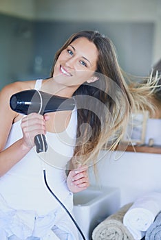 Im getting ready to have a good hair day. Portrait of a beautiful young woman drying her hair with a hairdryer in the