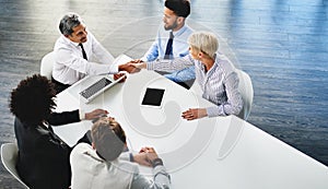 Im glad weve reached an agreement. businesspeople shaking hands during a meeting in an office.