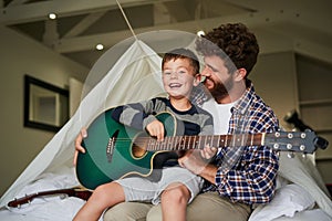 Im gonna be a musician. Cropped portrait of an adorable little boy sitting on his dads lap while learning to play the