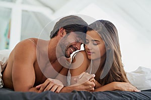Im so happy to be with you. Shot of a happy and affectionate young couple relaxing together in bed.