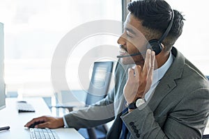 Im here to help. a young man wearing a headset while working in a call center.