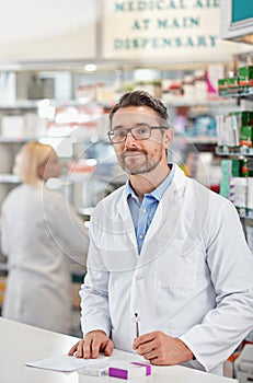 Im an important member of the healthcare community. a pharmacist at work with his colleague in the background. All