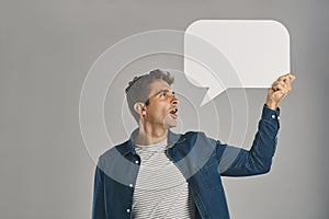 Im just gonna say it out loud. Studio shot of a young man holding a speech bubble against a grey background.