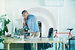 Im just heading out...a handsome young businessman making a phonecall while working in his office.