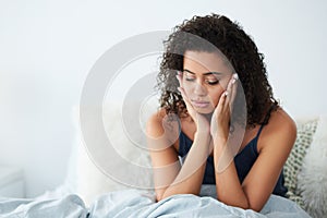 Im just so tired. an attractive young woman suffering from a headache and rubbing her head while in bed.
