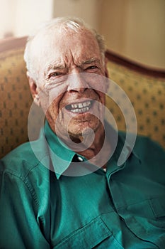 Im just a young man with wrinkles. Cropped portrait of a happy senior man sitting by himself in a living room.