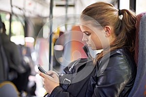 Im on my way. A teenage girl sending a text from her seat on the bus.