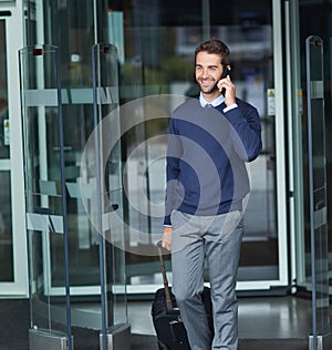 Im on my way there now. a handsome young businessman on the move with a suitcase while using his cellphone during the