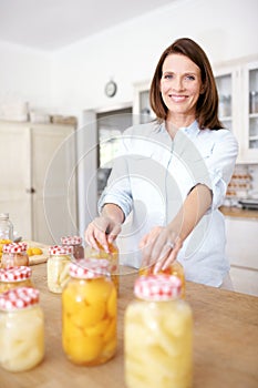 And Im nearly done...A mature woman resting her hands on two jars in the kitchen.