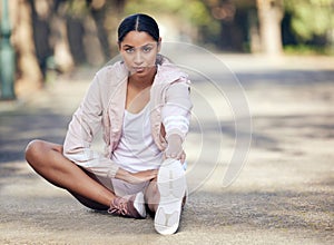 Im not here to mess around. Portrait of a sporty young woman stretching her legs while exercising outdoors.