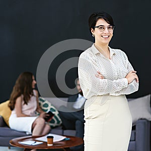 Im a part of the best in the business. Portrait of a young businesswoman standing in a modern office with colleagues in