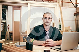 Im passionate about my craftsmanship. Portrait of a handsome young carpenter working on a laptop inside his workshop.