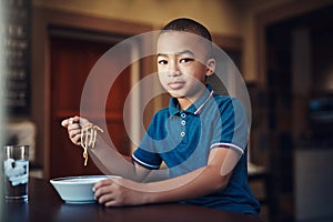 Im a picky eater but not when it comes to spaghetti. a young boy eating a bowl of spaghetti at home.