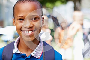 Im ready for a new school year. Confident african-american boy smiling at you with schoolmates in the background -