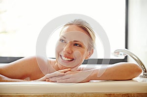 Im right where I need to be. A gorgeous young woman relaxing happily in a bathtub.