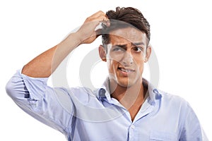 Im stumped. A handsome young man scratching his head in confusion against a white background. photo