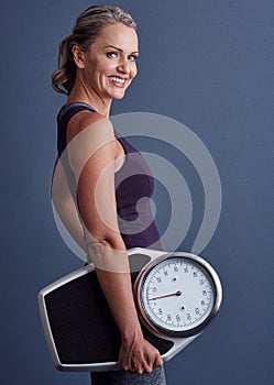 Im tipping the scales back in my favour. Studio portrait of an attractive mature woman holding a weightscale against a