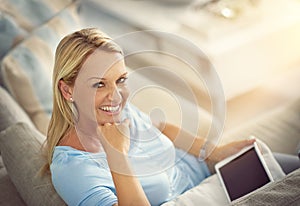 When Im wireless, Im stressless. a mature woman relaxing on the sofa with a digital tablet. photo