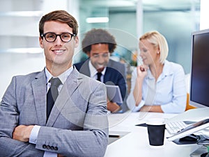 Im working on a secure financial future. Portrait of a smiling businessman sitting at his desk with staff in the