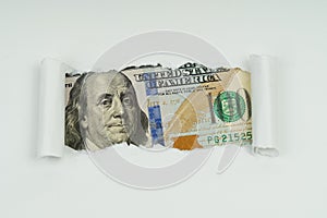 An image of a 100 dollar bill is visible in the torn hole of a sheet of paper