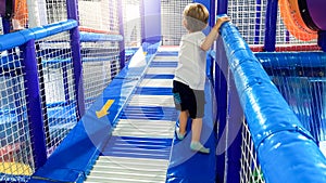 Image of 3 years old toddler boy climbing and crawling on the children palyground in shopping mall. There are lots of