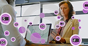 Image of 5g and symbols in circles over diverse coworkers using laptop and digital tablet