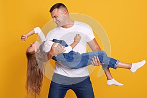 Image of adorable kid girl with her father, handsome man holding child in hands, wearing casual clothing, father and his little