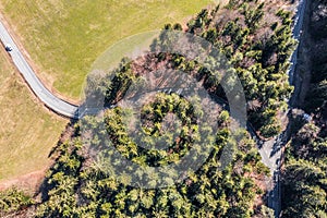 Image of aerial shot with drone of a road in dense conifer forest in spring with cars, Germany