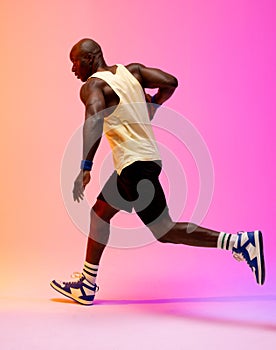 Image of african american basketball player with basketball on neon orange to pink background