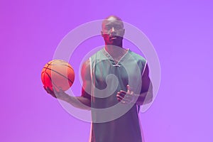 Image of african american basketball player with basketball on neon purple background