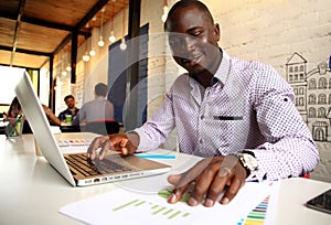 Image of african american businessman working on his laptop. Handsome young man at his desk photo