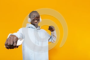 Image of african american guy in headphones smiling and holding cellphone