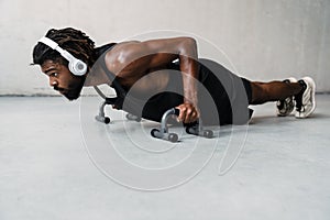 Image of african american sportsman working out with push-up stops