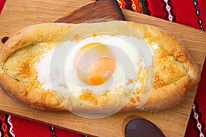 An image of an Ajarian khachapuri on table with raw egg close up